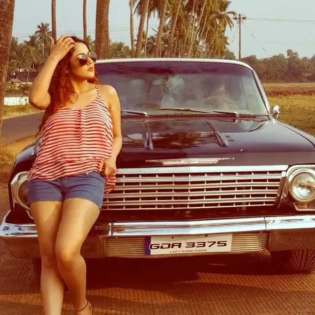 Shehnaz Gill posing with a car